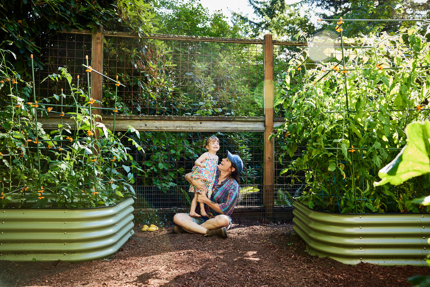 mother and child in garden with tomato plants in raised bed garden